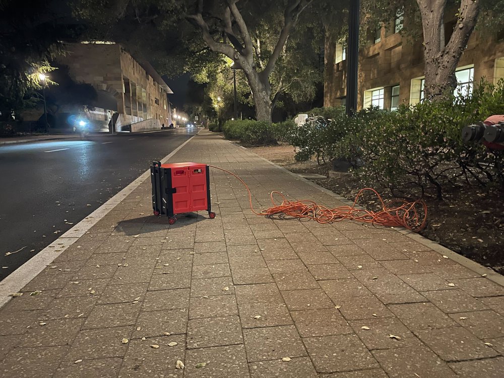 Outdoor walkway at night with a red slatted crate on the pavement