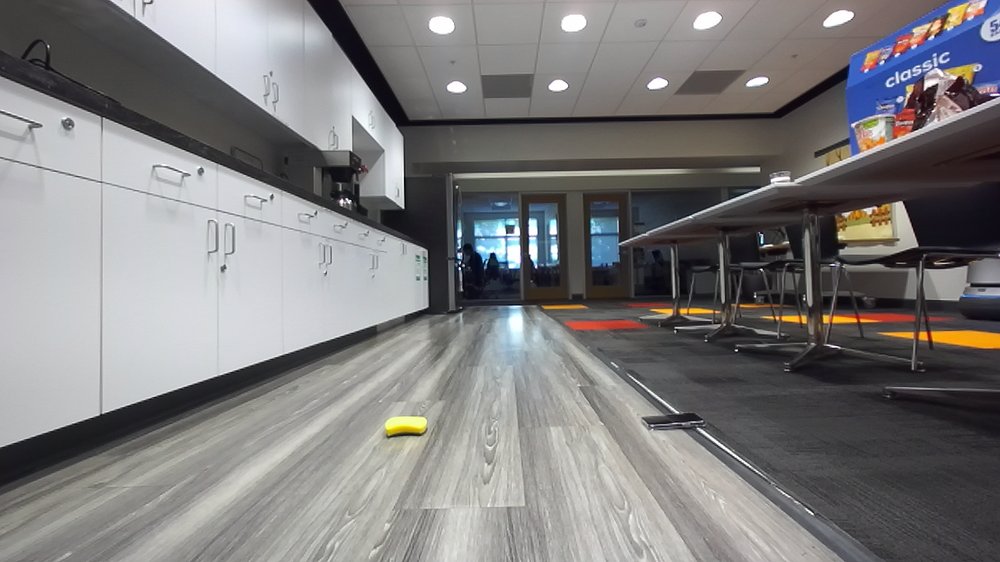 Indoor cafe corridor with a small object on the floor ahead of the robot