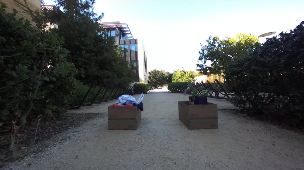 Outdoor gravel path in daylight blocked by two wooden crates