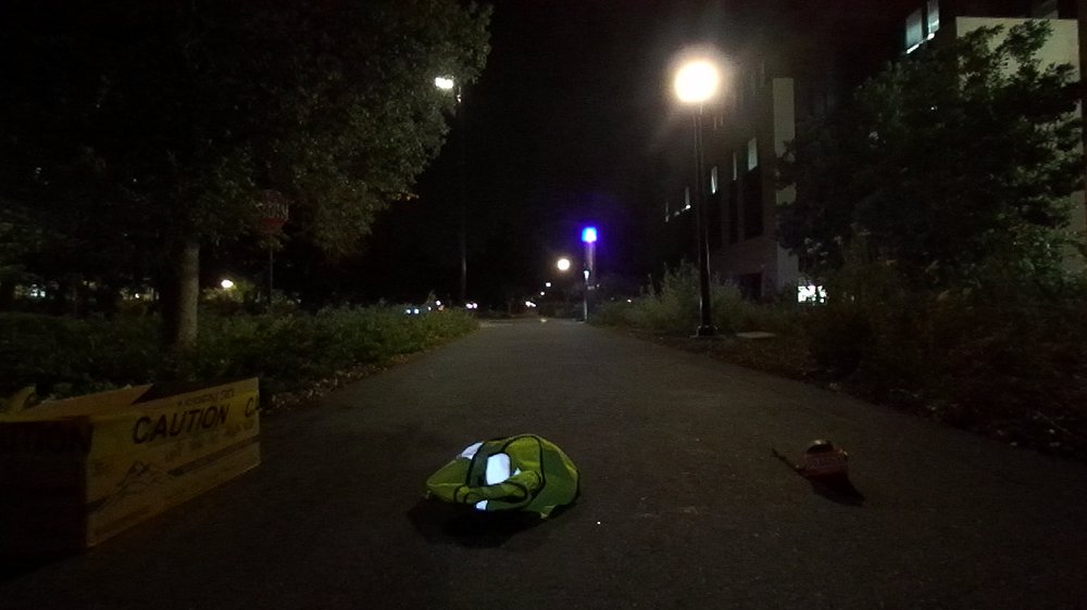 Outdoor walkway at night with a caution crate and a bag on the path